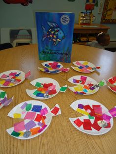 paper plates with fish cut out of them sitting on a table next to a book