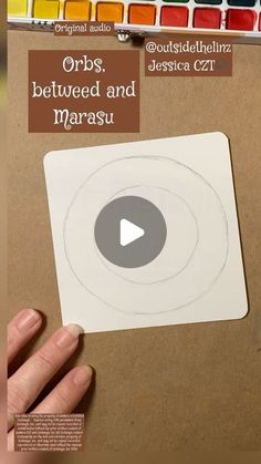 a person holding up a sticker with the words orbs between and marsu on it