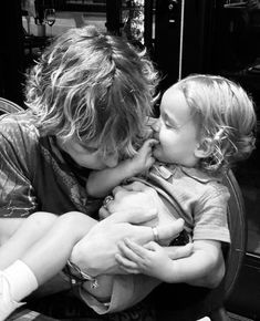 a woman kissing a small child on the cheek