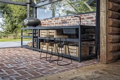 an outdoor bar with stools and tables in front of a brick wall that has glass doors