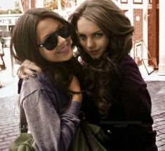 two young women standing next to each other with their arms around one another and smiling at the camera