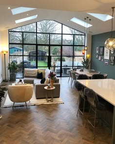 a living room filled with furniture next to a large glass wall window on top of a hard wood floor