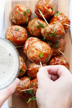 someone is dipping sauce on meatballs with toothpicks and parsley in the middle