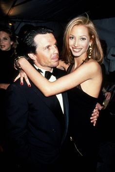 a man in a tuxedo hugging a beautiful woman at an event stock photo