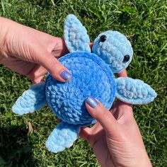 a person holding a small blue turtle in their hand