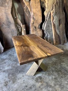 a wooden table with metal legs in front of some rocks and wood planks on the floor