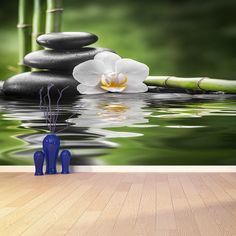 a wall mural with white flowers and bamboo sticks in the water next to some black rocks