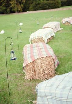 several hay bales are lined up in the grass with umbrellas on each side