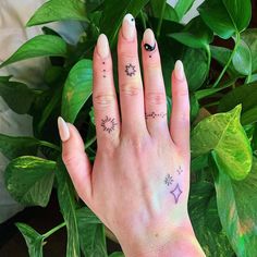 a woman's hand with two small tattoos on her fingers and the other finger