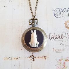 A fully working bronze pocket watch with a detailed charcoal and cream rabbit cameo in the centre is suspended on a long antiqued bronze chain. Choose your length from the drop down menu. The necklace is antiqued bronze with a lobster clasp. The watch is 1 3/8 inches (35 mm) in diameter, and pops open when you press the button at the top. (there's protective film to remove when you receive it). A battery is already inside the watch. This necklace is gift boxed. White Rabbit Pocket Watch, Watch Diy, Pocket Watch Necklace, Cameo Necklace, Oval Earring, White Rabbit, Hammered Silver, Watch Necklace, Gold Plated Chains