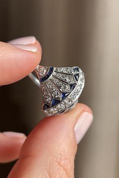 Antique Art Deco dinner ring, featuring tapering lines of old single cut diamonds with bright blue and angular calibré sapphires. It expresses highly architectural Egyptian Revival detail and delicate openwork. Made in a comfortable platinum setting with millegrain detail. Circa 1920. Ruby Cocktail Ring, Erstwhile Jewelry, Art Deco Egyptian, Dinner Ring, Antique Costume Jewelry, Edwardian Jewelry, Art Deco Diamond Rings, Egyptian Revival, Indian Wedding Jewelry