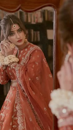 a woman in an orange outfit is looking at herself in the mirror and she has her hand on her face