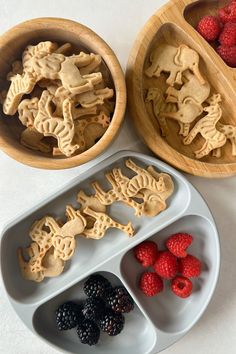 three trays filled with cookies and raspberries on top of a white table