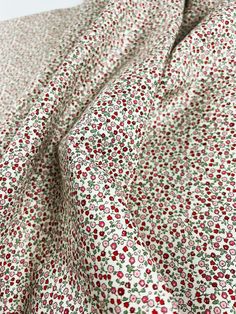 a red and white flowered fabric with small flowers on it's side,