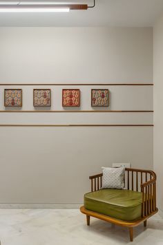 a green chair sitting in front of three framed pictures on the wall next to each other