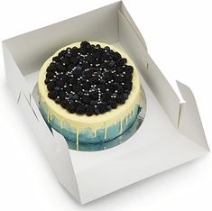 a cake in a box with blackberries and blue icing on it's top