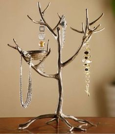 a silver tree with earrings on it sitting on a table next to a potted plant