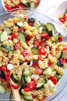 a bowl full of pasta salad with cucumbers, tomatoes and black olives