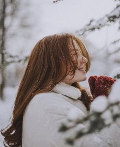 a woman standing in the snow with her mittens on