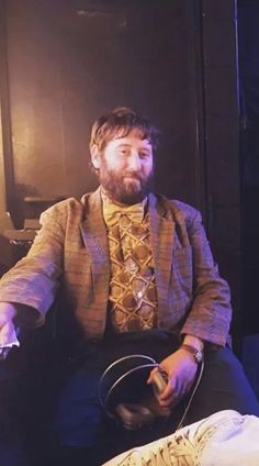 a man sitting in a chair holding a steering wheel while wearing a suit and tie