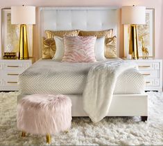 a white bed with pink and gold pillows on top of it next to two lamps