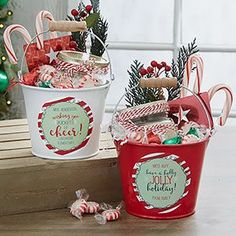 two buckets filled with candy canes and candies on top of a wooden table