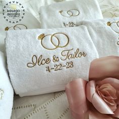 two towels with wedding rings on them and a pink rose laying next to each other