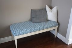 a blue and white bench with two pillows on it next to a wall in a room