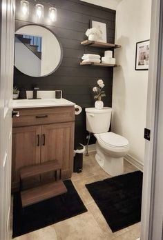 a white toilet sitting next to a wooden cabinet in a bathroom under a round mirror