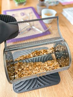 a close up of a person using a grater to scoop seeds into a container