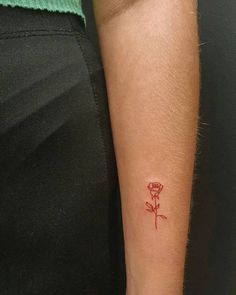 a woman's arm with a small red rose tattoo on the left side of her arm