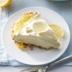 a slice of lemon pie on a white plate with fork and knife next to it