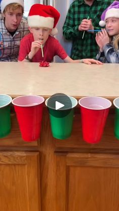 a group of people sitting around a table with cups in front of them and santa hats on