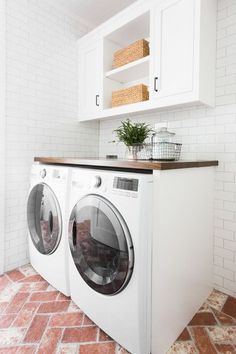 a washer and dryer in a white laundry room with red tile flooring