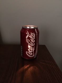 a coca cola can sitting on top of a wooden table