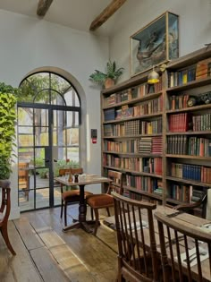 an old library with wooden chairs and tables in front of large open doors that lead to the outside