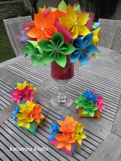 colorful paper flowers sitting on top of a wooden table