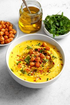 the bowl is full of soup and garnished with chopped chickpeas, cilantro, and parsley