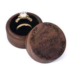 a wooden ring box with an engraved message on the lid and a wedding band in it