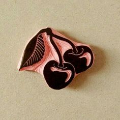 a pink and black brooch sitting on top of a white table next to a brown wall