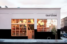 the storefront of tartine is lit up with yellow lights and balloons hanging from the windows