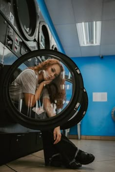 a woman sitting on the floor in front of a dryer looking at her reflection