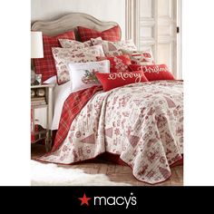 a bed with red and white comforters on top of it next to a night stand