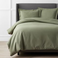 a bed with green sheets and pillows in a room