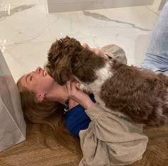 a woman holding a brown and white dog on top of her back while she is petting it's face