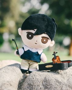 a stuffed toy with a violin on top of a rock