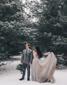 a bride and groom are standing in the snow with their wedding dress flowing over them