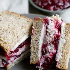 a sandwich cut in half with cranberry sauce on the side and another plate next to it