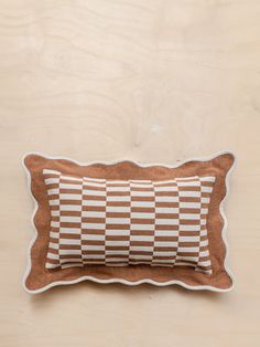 a brown and white checkered pillow sitting on top of a wooden table next to a wall