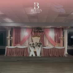 an image of a stage set up for a wedding ceremony with pink drapes and white chairs